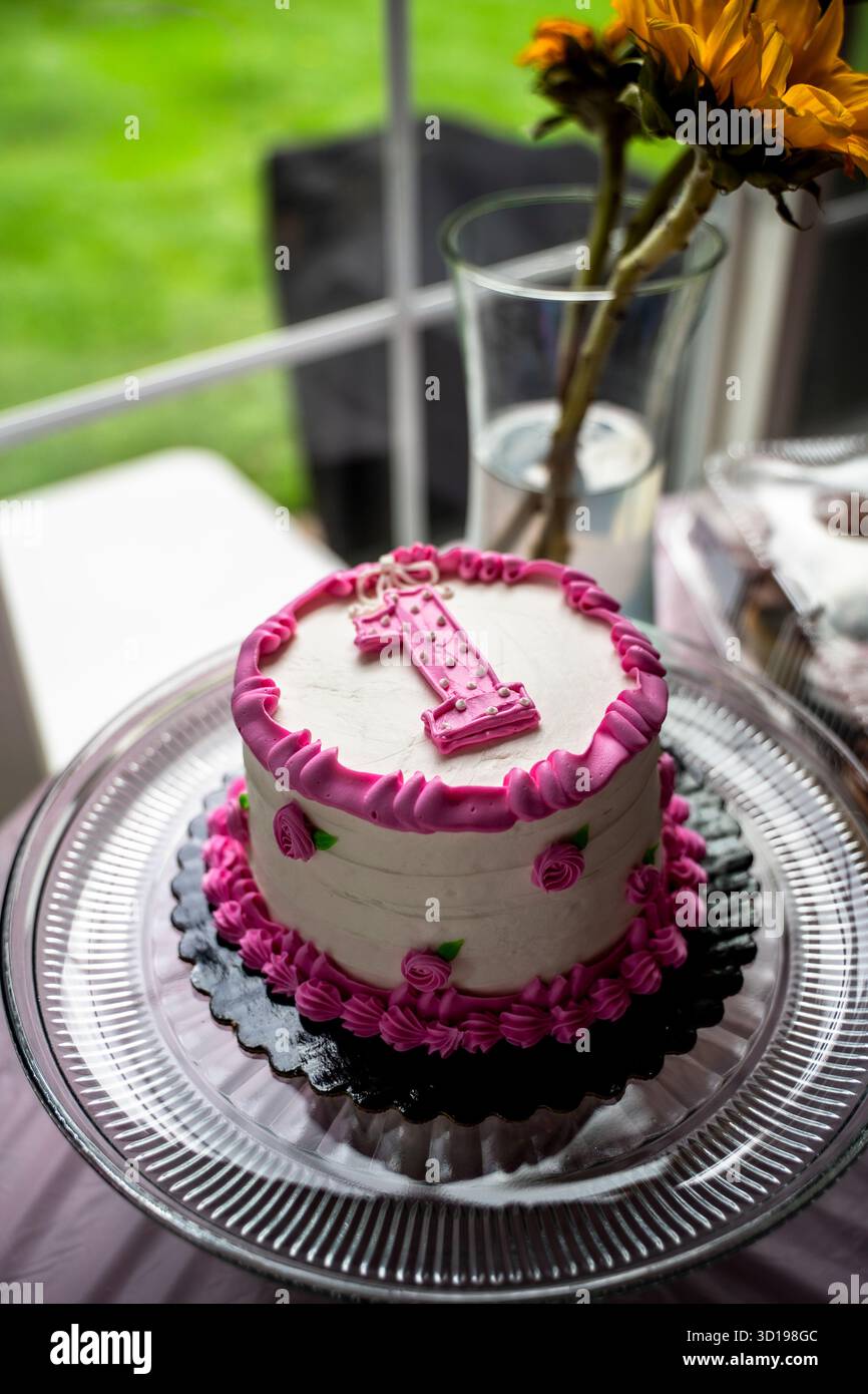 Gâteau Smash premier anniversaire rose et blanc sur plaque à gâteau dans Windowlight Banque D'Images