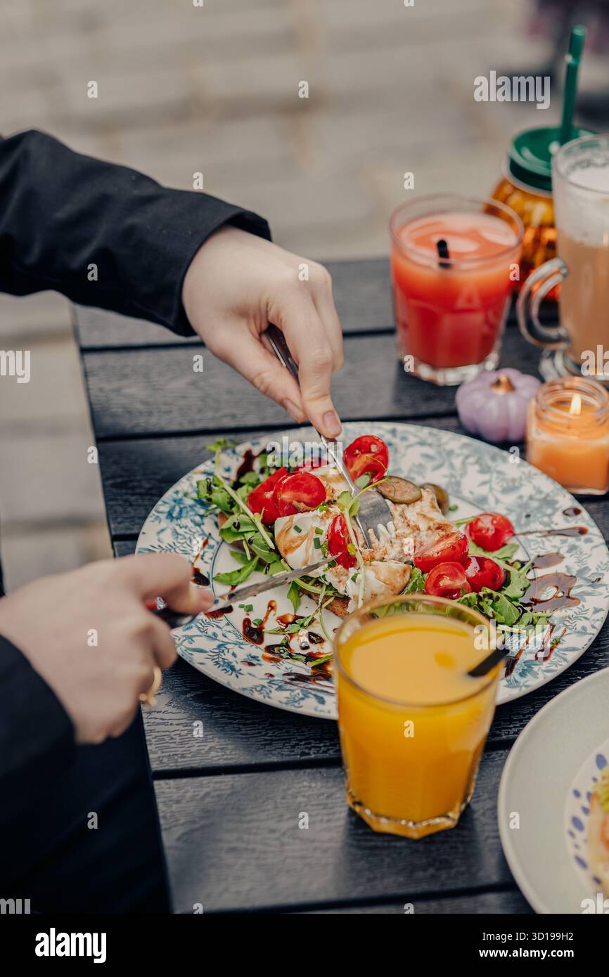 Fille coupant un croissant avec un couteau et une fourchette Banque D'Images