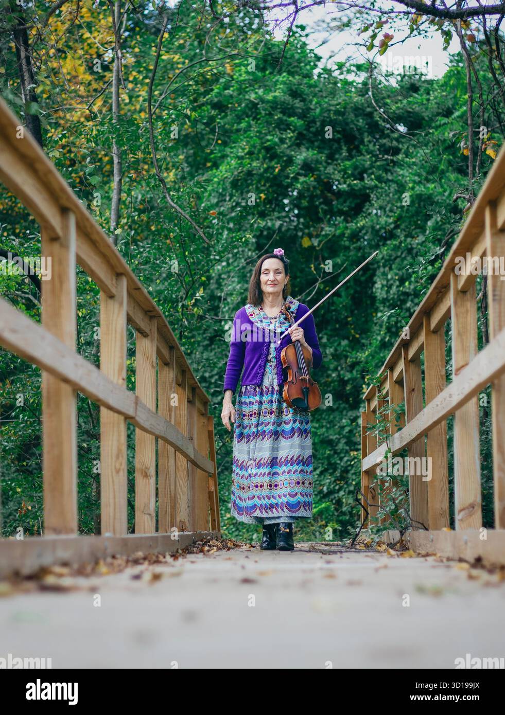 Une femme se tient debout sur un pont de bois tenant un violon Banque D'Images