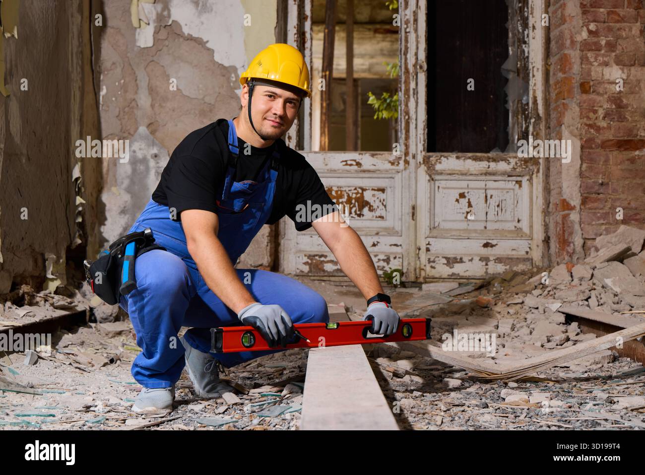 Travailleur de la construction mesurant une poutre en bois dans un chantier de rénovation Banque D'Images