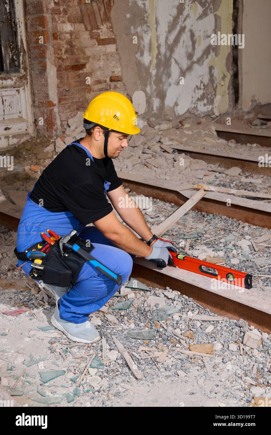 Travailleur de la construction nivele le plancher dans une rénovation de vieux bâtiment Banque D'Images