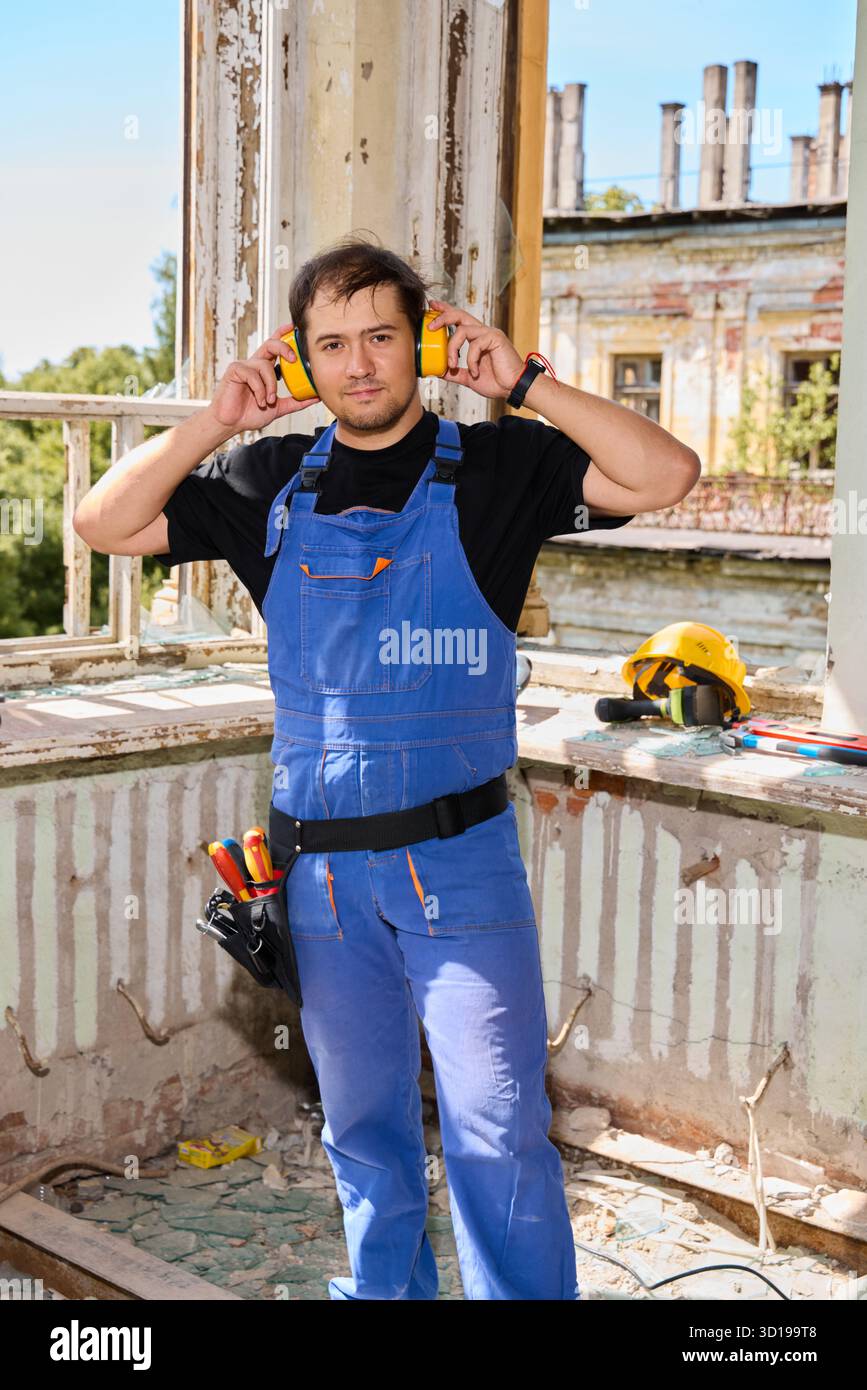 Le travailleur de la construction se prépare à la tâche sur un chantier de rénovation Banque D'Images