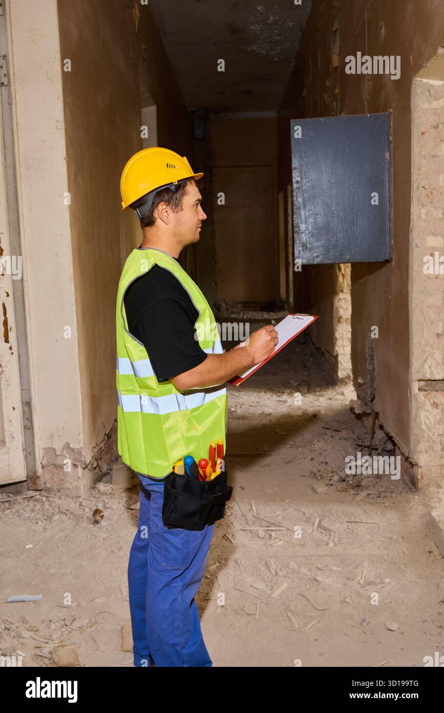 Travailleur inspectant le chantier de construction, portant un équipement de sécurité et un casque Banque D'Images