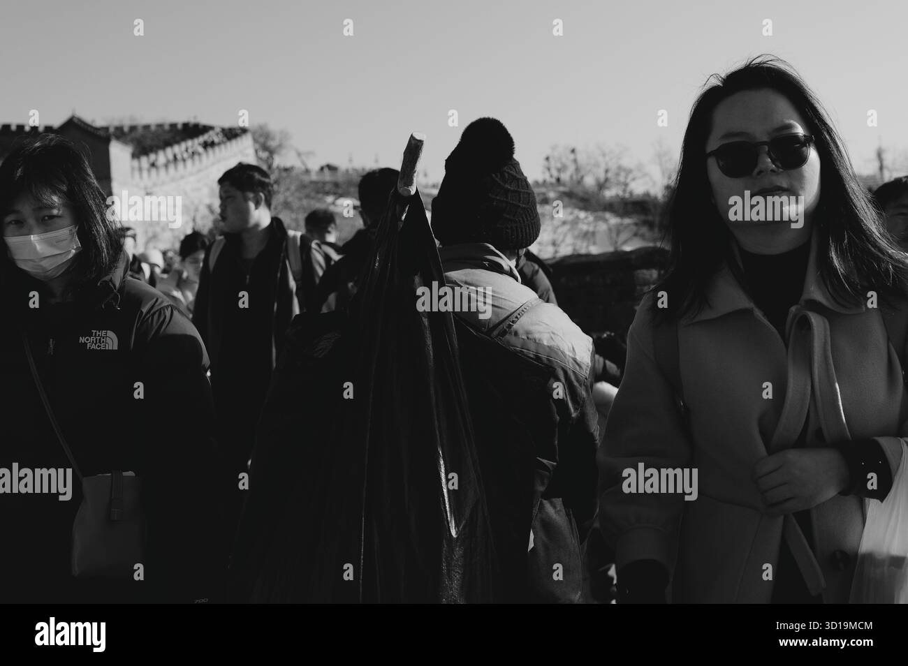 Un travailleur sanitaire transportant un grand sac poubelle se déplace à travers une foule dense sur la Grande Muraille de Chine Banque D'Images