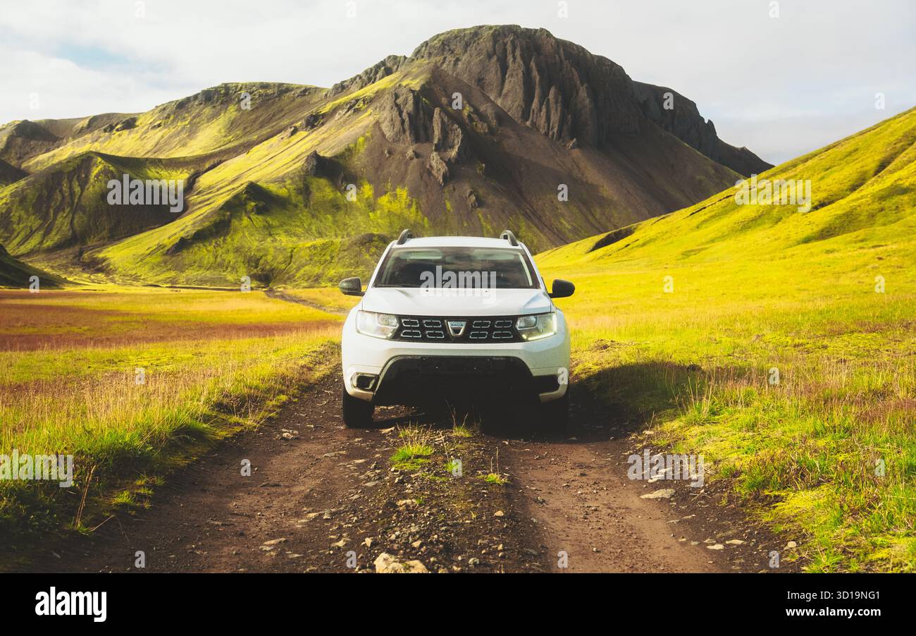 F208, Islande - 30 août 2025 : vue d'un Dacia Duster blanc garé sur un chemin rocheux, encadré par des collines verdoyantes sous un vaste ciel, créant un sentiment d'aventure. Banque D'Images