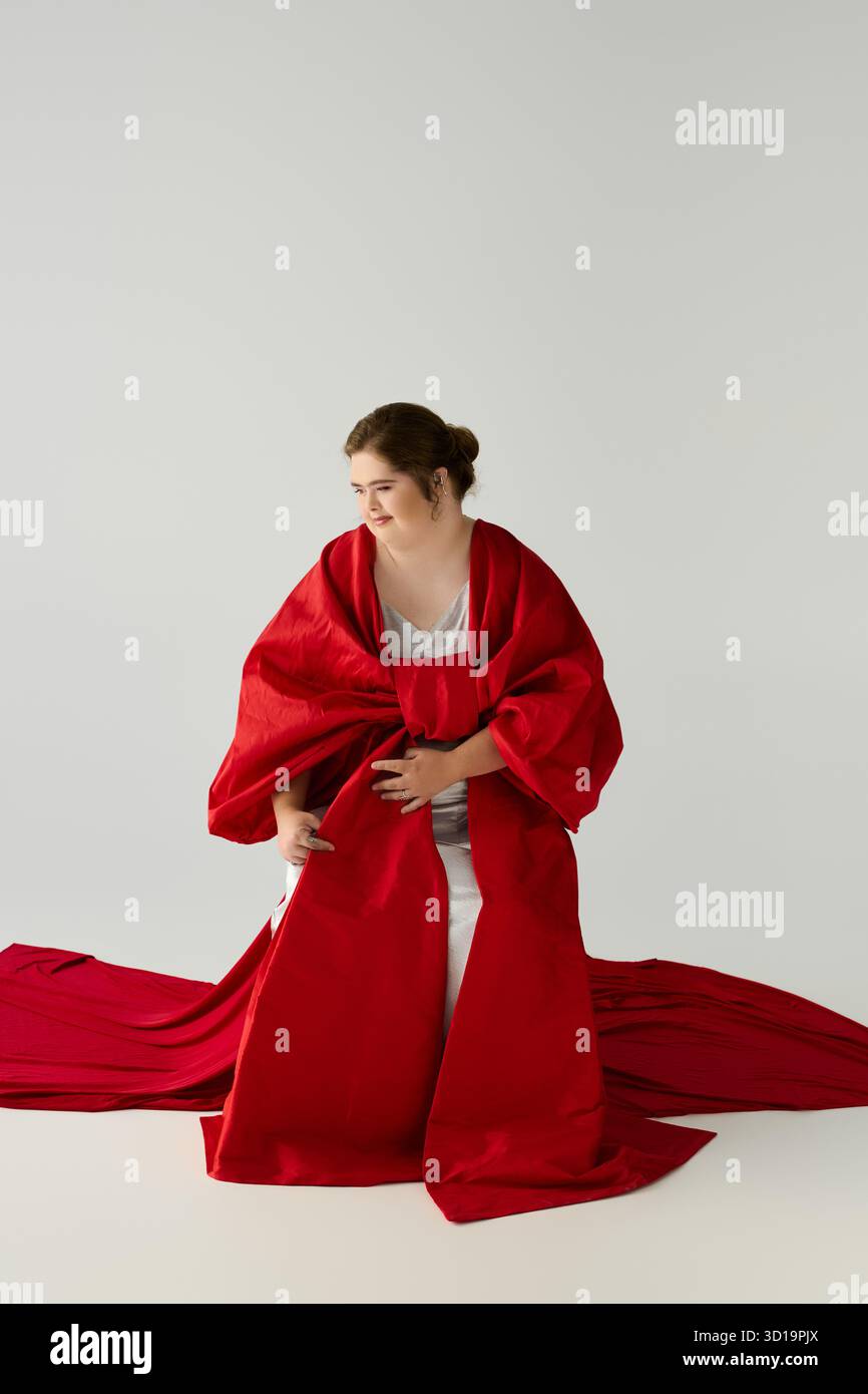 Une jeune femme avec des poutres du syndrome de Down dans sa luxueuse tenue rouge, pleine de chaleur et de confiance. Banque D'Images
