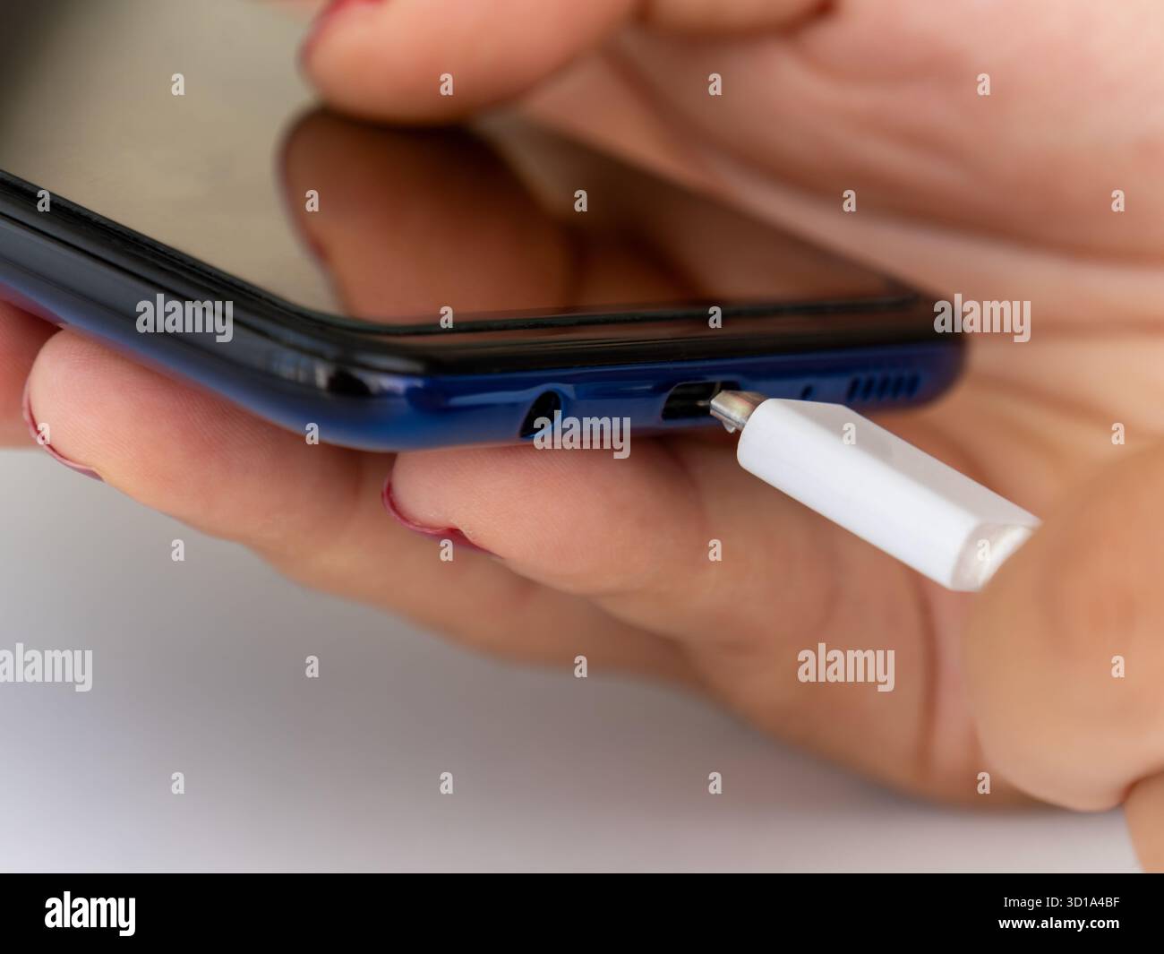Main de femme insérant le chargeur dans le téléphone mobile intelligent. Connexion du câble de chargement USB-C au téléphone. Banque D'Images