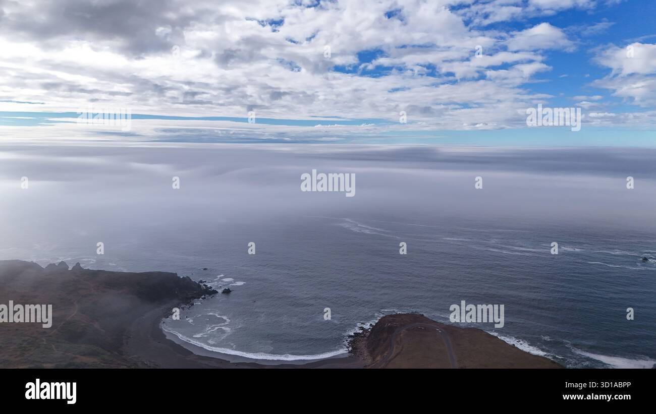 Vue aérienne de la rencontre de la terre, de la mer et du ciel où l'horizon brumeux brouille la ligne entre l'eau et l'atmosphère, créant une scène côtière sereine et éthéré. Banque D'Images