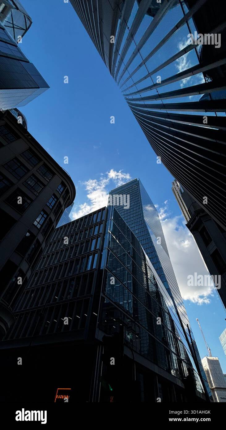 Vue vers le haut des gratte-ciels modernes en verre et en acier dans un centre-ville urbain sous un ciel bleu clair. - Image de stock capturée avec un smartphone