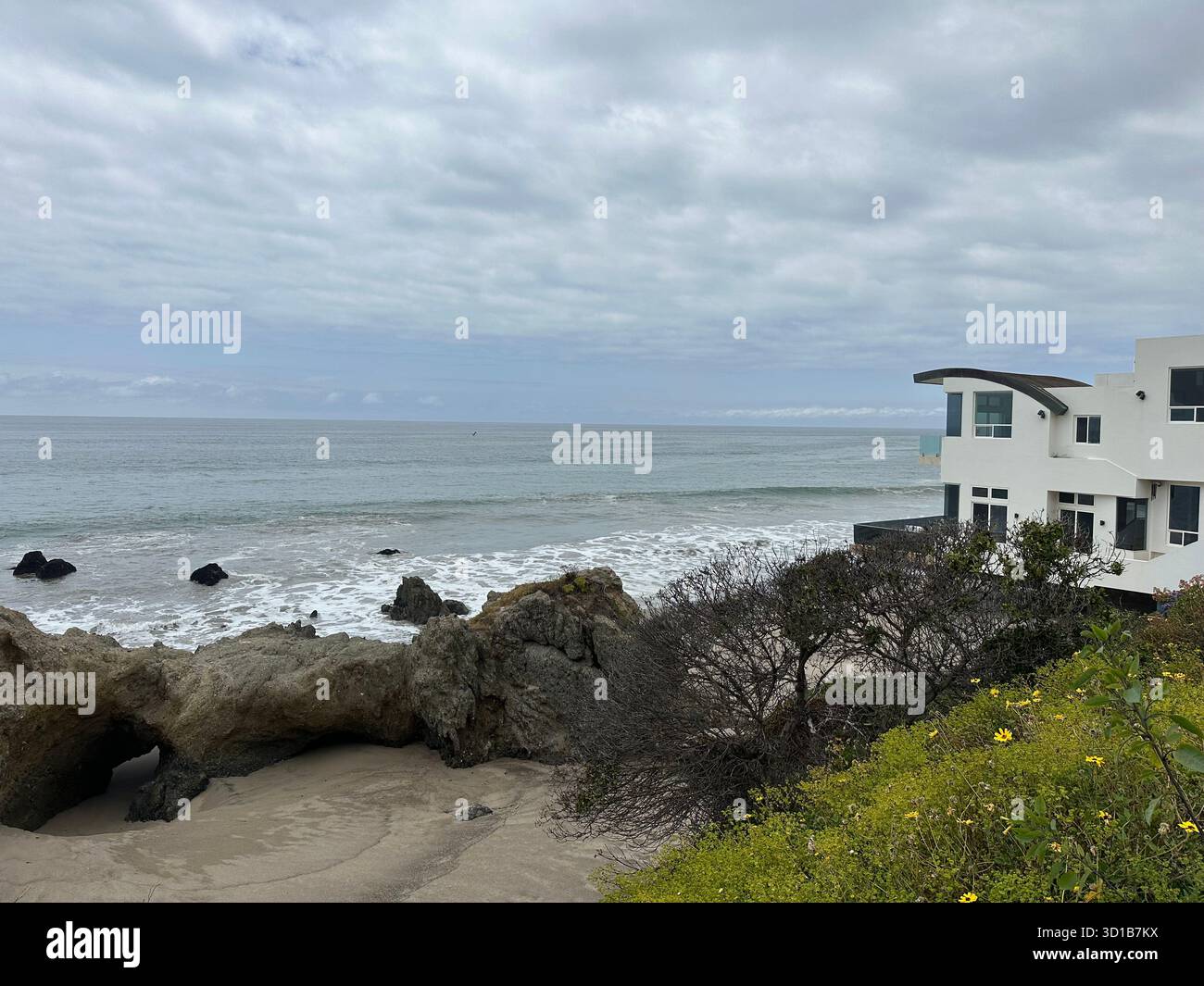 Vagues océaniques s'écrasant sur la rive rocheuse près de maisons côtières en Californie, États-Unis. Vue panoramique sur la mer sous ciel nuageux - Image de stock capturée avec un smartphone