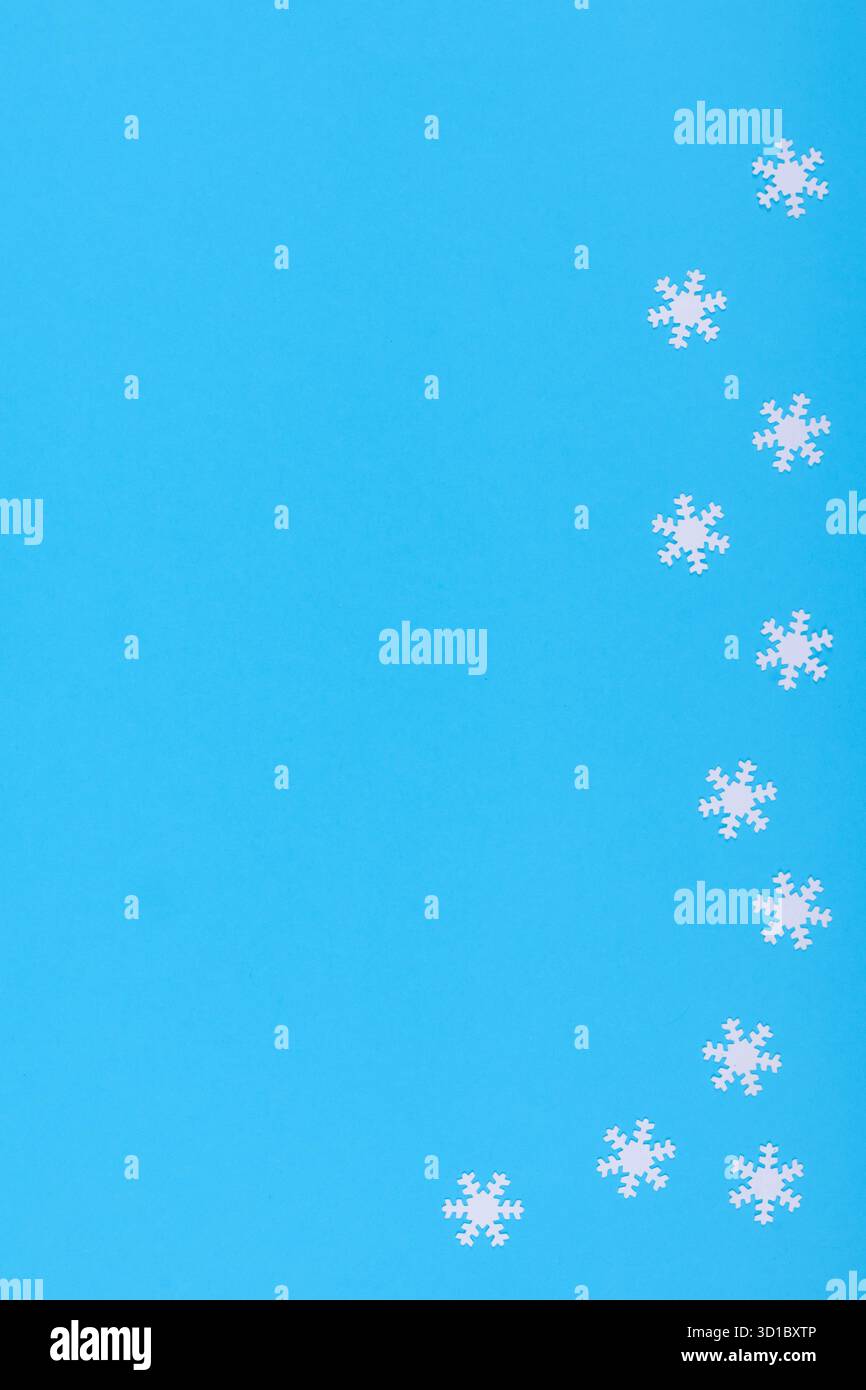Fond d'hiver minimaliste avec des flocons de neige en papier blanc disposés sur une surface bleu vif Banque D'Images