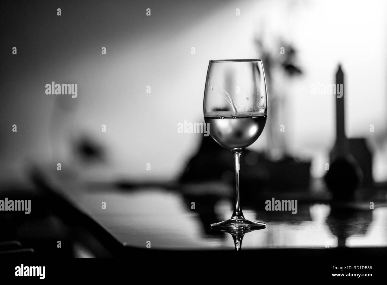 Faible profondeur de champ (mise au point sélective) détails avec un verre de vin blanc sur une table dans une pièce sombre avec contre-jour. Banque D'Images