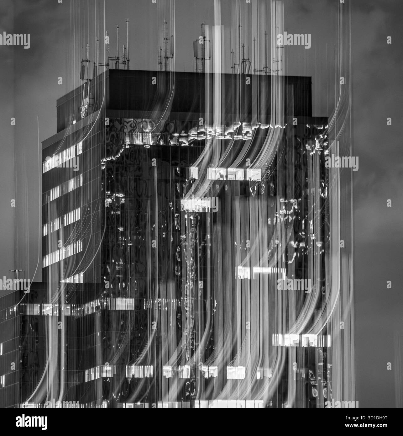 Abstrait longue exposition d'un immeuble de bureaux de ville illuminé la nuit en monochrome, avec des stries lumineuses de mouvement et une atmosphère urbaine spectaculaire. Banque D'Images