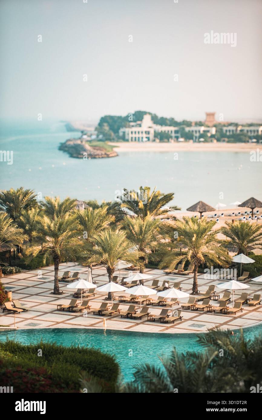 Complexe balnéaire tropical avec palmiers et chaises longues surplombant l'océan. Destination de vacances luxueuse avec belle vue sur la mer. Banque D'Images