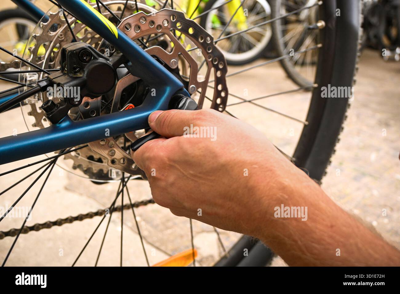 Main ajustant le frein à disque sur un vélo, effectuant l'entretien dans un magasin de vélo. Banque D'Images