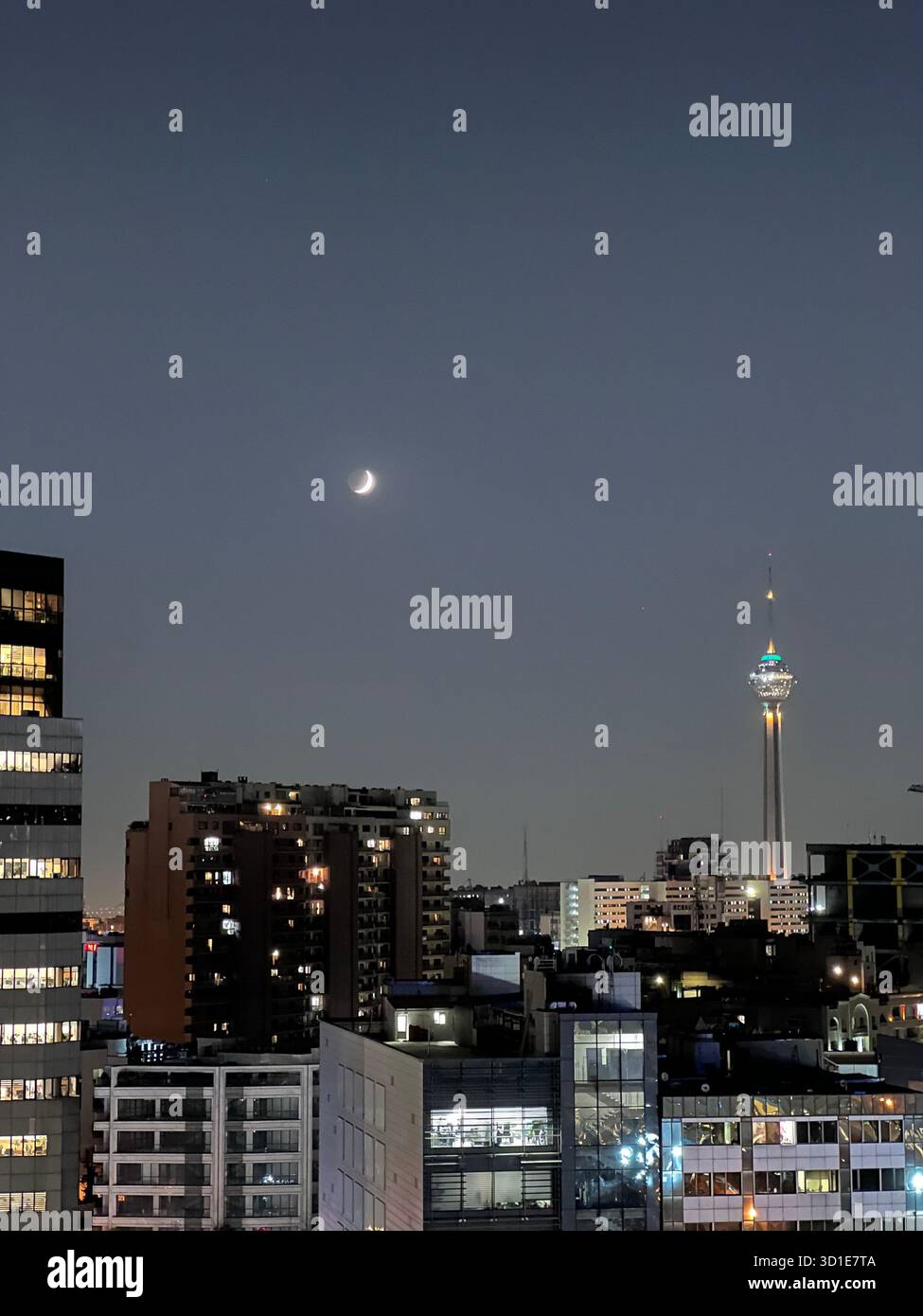 Vue nocturne de Téhéran, Iran - la Tour Milad brille sous un croissant de lune au-dessus de la ligne d'horizon lumineuse de la ville. Banque D'Images