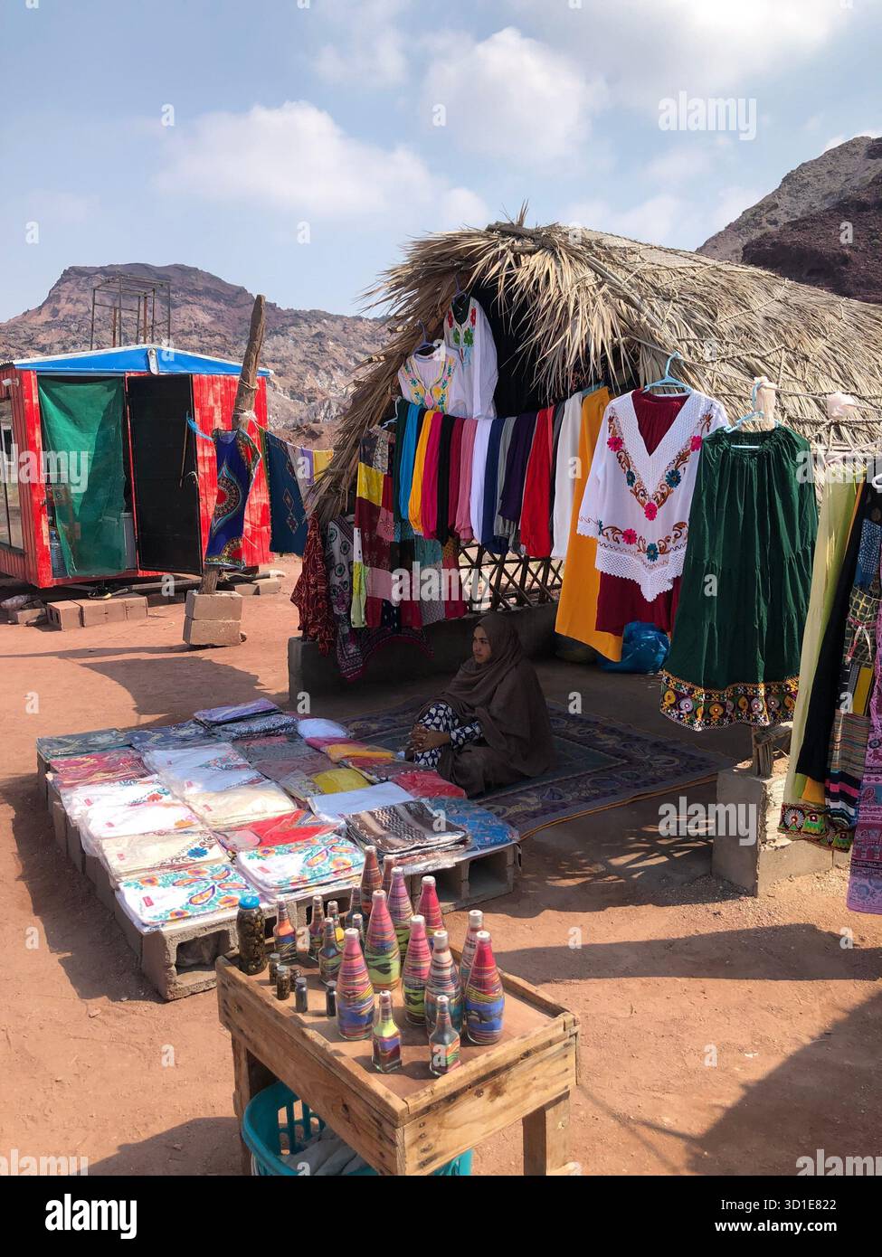 Une femme locale vendant de l'artisanat fait à la main et des vêtements colorés dans un marché traditionnel sur l'île d'Hormuz, en Iran. Banque D'Images