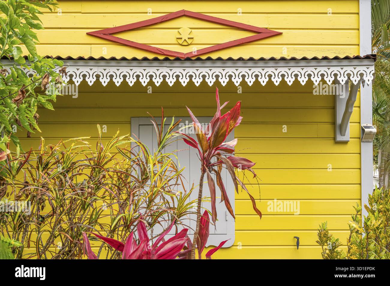 La vue détaillée d'une maison traditionnelle en bois créole avec une façade jaune vif montre le losange rouge comme un symbole protecteur 'Magic eye†under t Banque D'Images