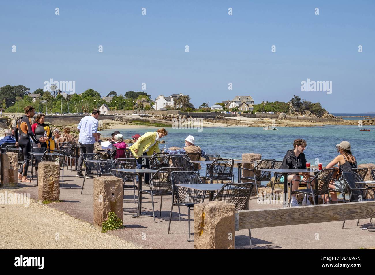 De nombreux invités s'assoient à de petites tables sur la terrasse ensoleillée du Grand Hôtel du Port Blanc sur les rives de la Manche, bordée par pi Banque D'Images