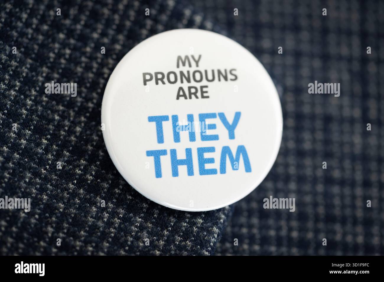 Un badge portant les mots « My pronoms are They » est porté sur le revers d'un blazer bleu Banque D'Images