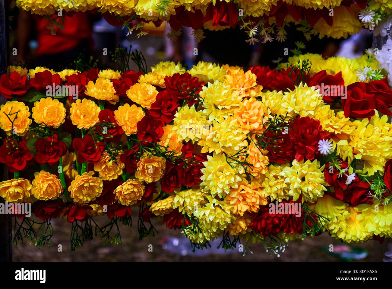 Chrysanthèmes jaune vif et guirlande florale de roses rouges pour la célébration, la décoration et la floraison festive Banque D'Images