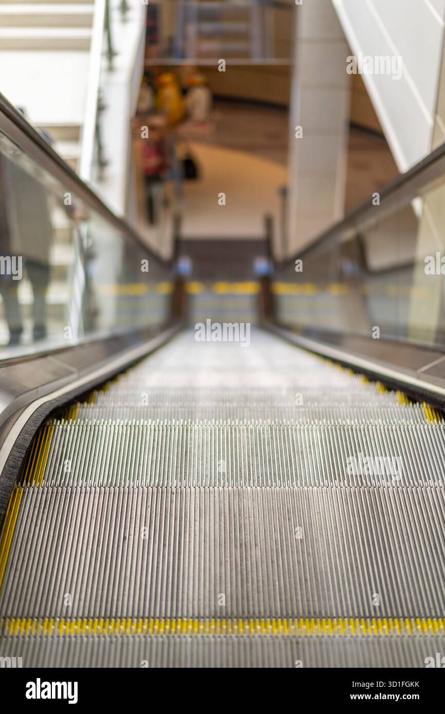 Vue rapprochée d'un escalier roulant d'un centre commercial britannique, depuis la marche supérieure jusqu'à l'étage inférieur lointain. Banque D'Images