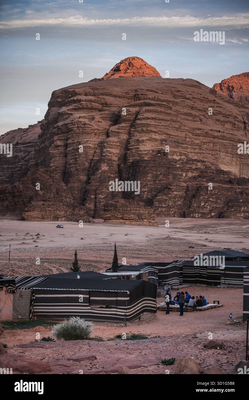 Vue large des tentes de style bédouin dans le désert de Wadi Rum, Jordanie, 2024. Les touristes se sont rassemblés près des falaises de grès dans la lumière de fin d'après-midi. Banque D'Images