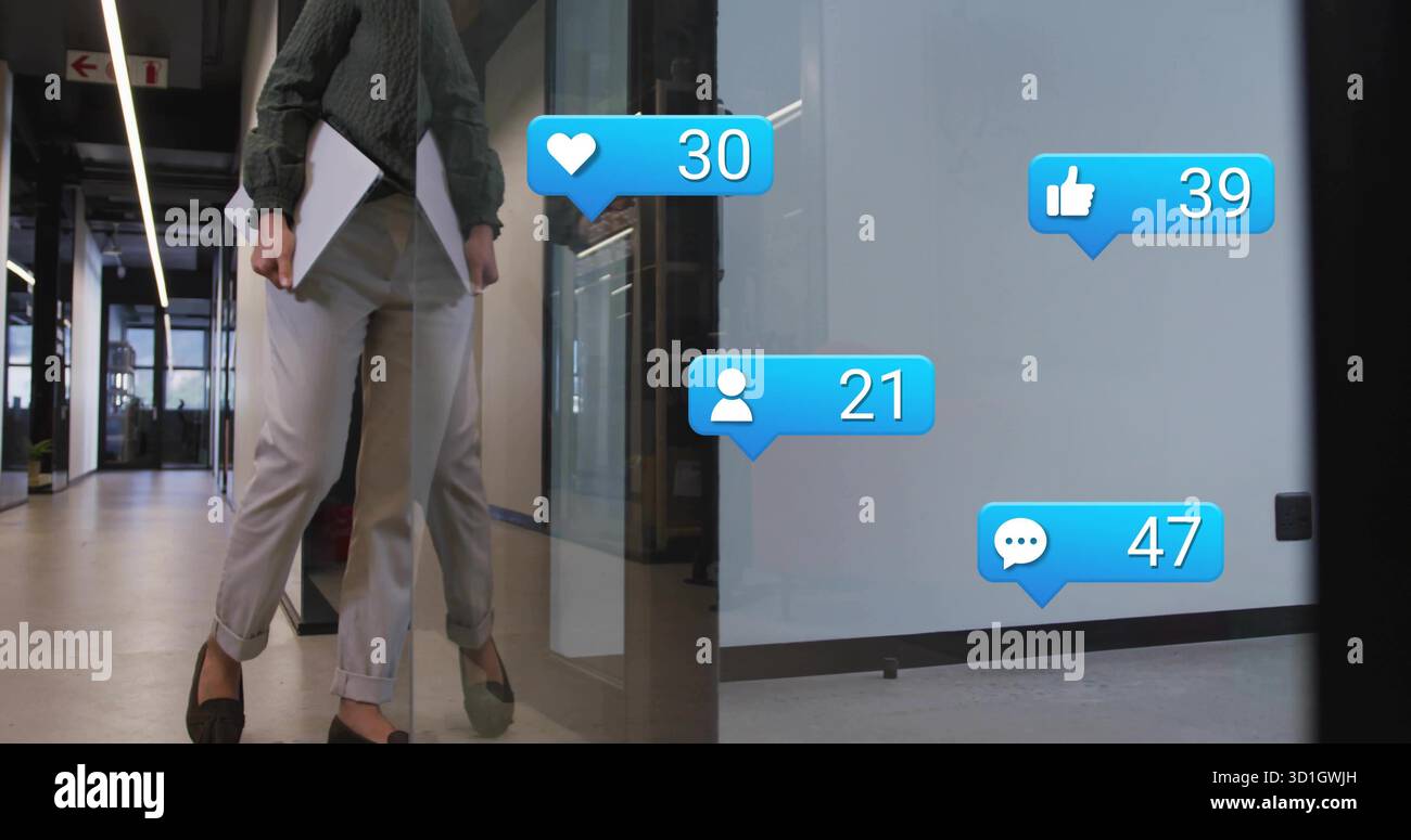 Femme asiatique marchant tenant un ordinateur portable à la hanche dans le couloir de bureau, avec des icônes flottantes de médias sociaux Banque D'Images