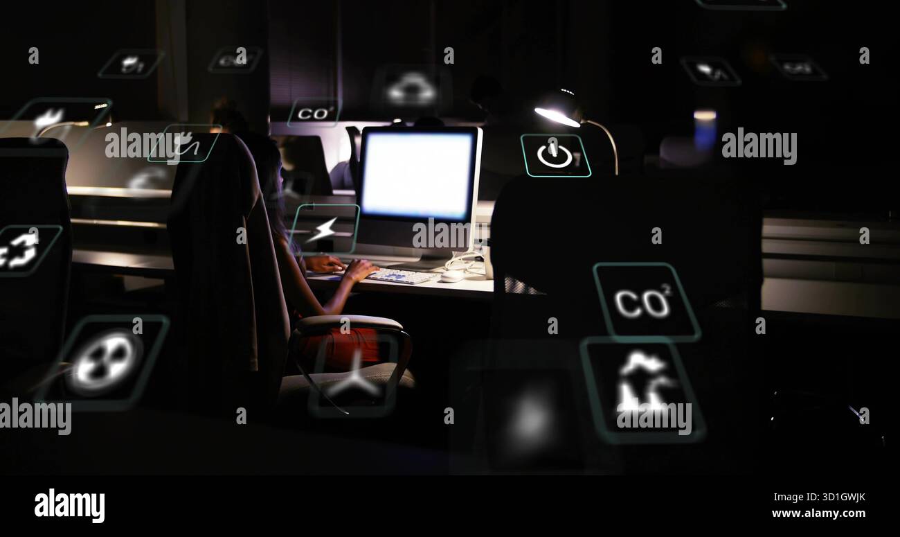 Surveillance des mesures écologiques ingénieur féminin travaillant sur l'ordinateur dans le bureau la nuit avec des icônes flottantes Banque D'Images