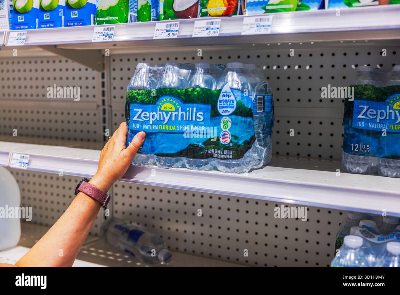 Vue rapprochée d'une femme prenant Zephyrhills paquet d'eau embouteillée de l'étagère du supermarché CVS. Miami Beach. ÉTATS-UNIS. Banque D'Images