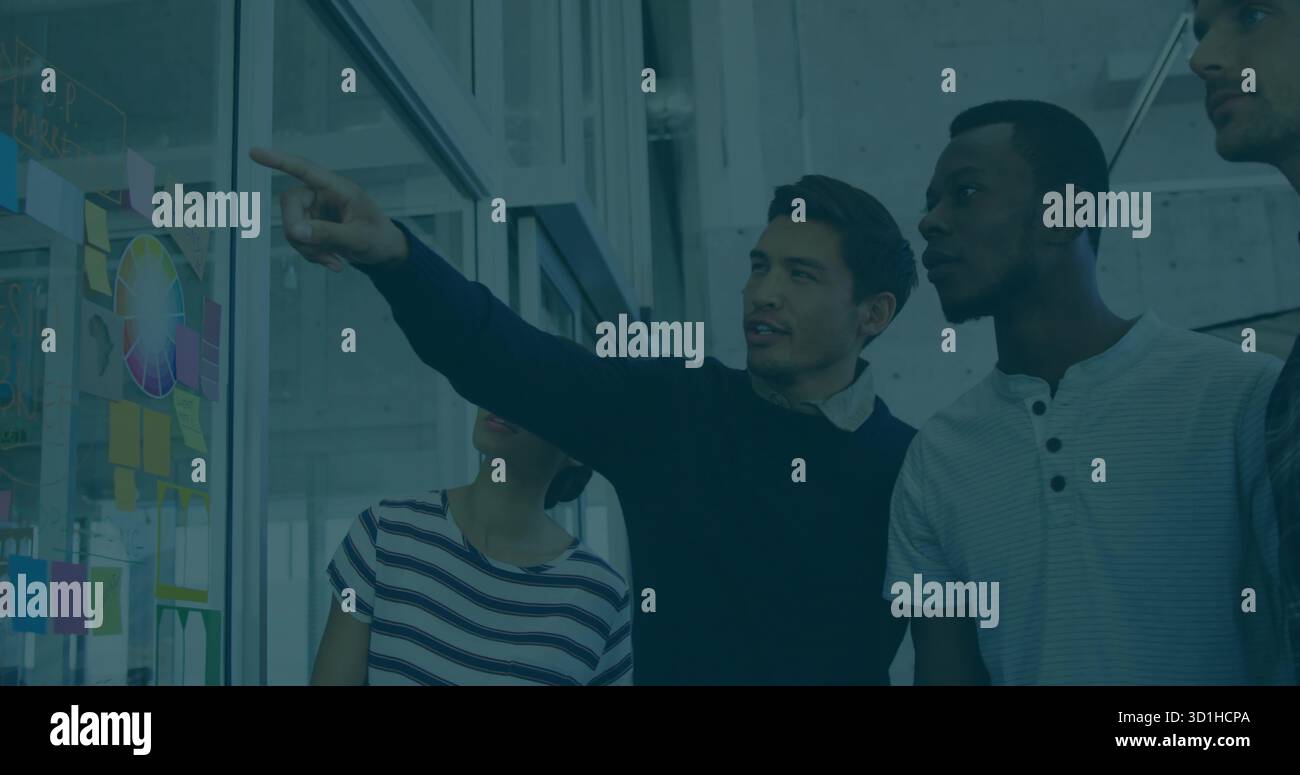 Pointage homme en pull marine mettant en évidence la roue de couleur sur le tableau blanc en verre dans le bureau, notes collantes Banque D'Images