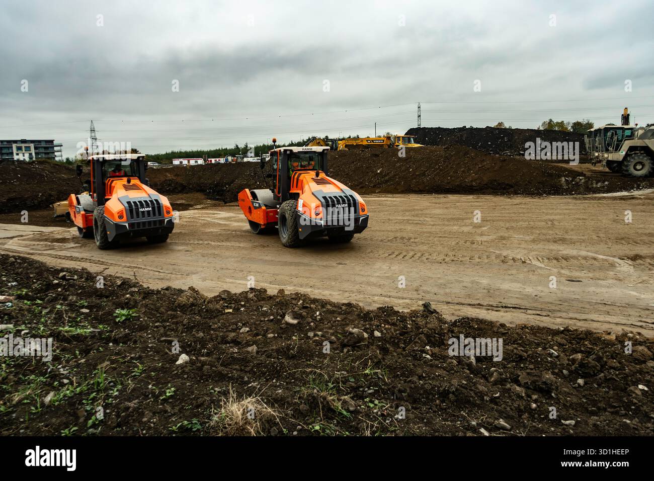 Chantier de construction à Dublin, Irlande avec deux rouleaux HAMM orange compactant le sol, préparant les terrains pour le développement sous ciel couvert. Banque D'Images