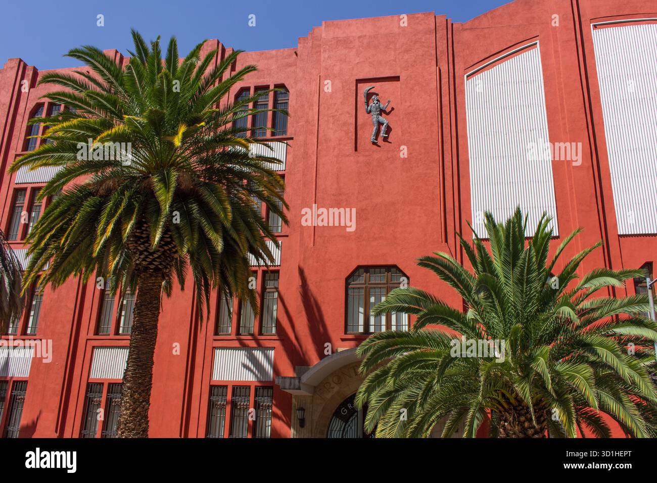Bâtiment Art déco rouge vif avec palmier à Mexico - architecture géométrique et façade moderniste sous la lumière du soleil Banque D'Images