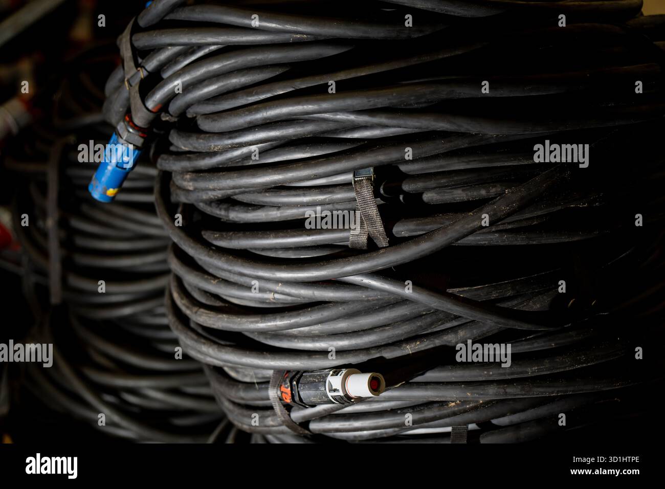 Câbles d'alimentation industriels enroulés avec connecteurs utilisés pour les connexions électriques lourdes et la distribution d'énergie dans l'atelier ou la construction Banque D'Images