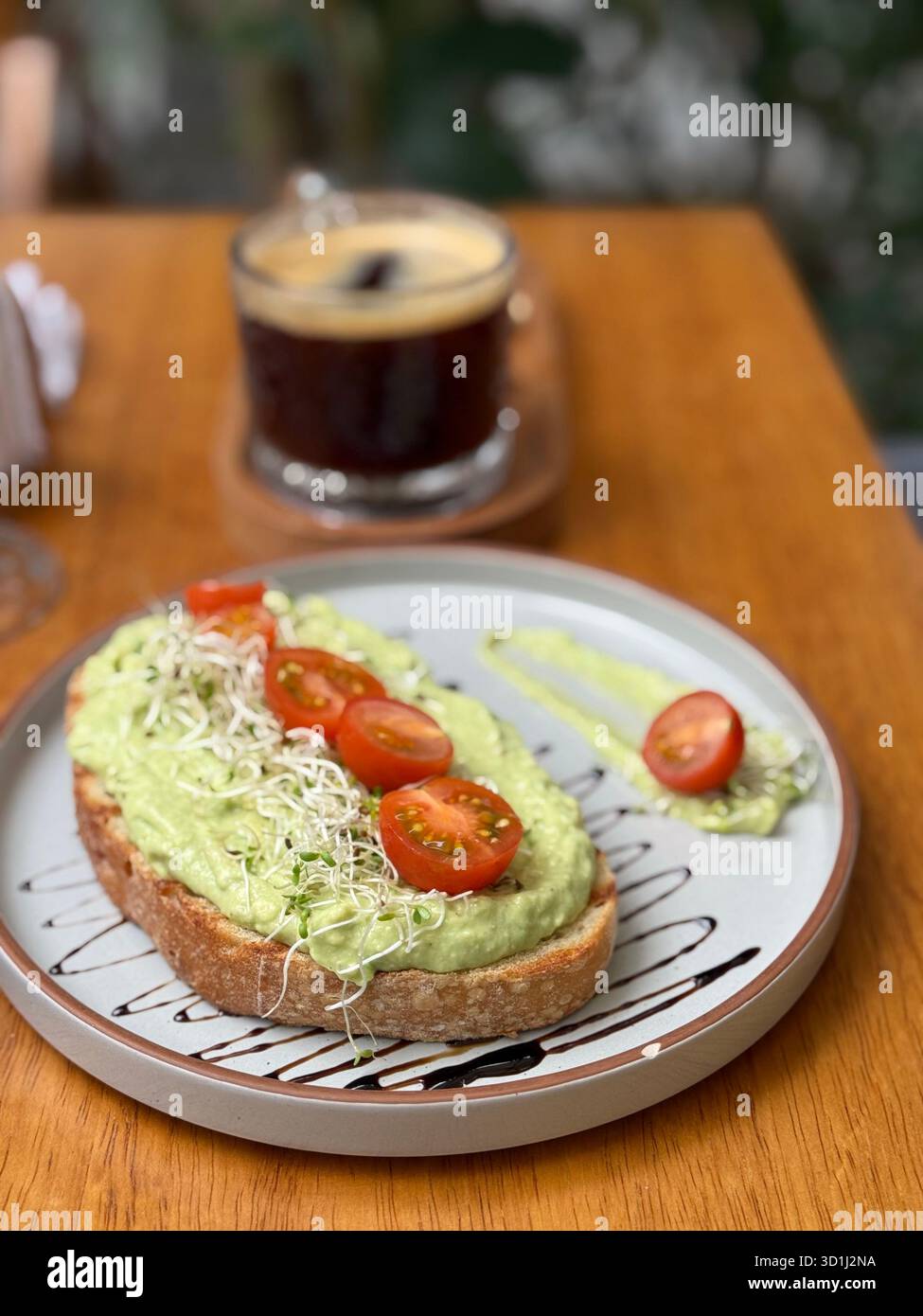 Pain grillé à l'avocat frais garni de tomates cerises et de germes servis avec du café noir dans un café extérieur confortable à Lima, au Pérou - Image de stock capturée avec un smartphone