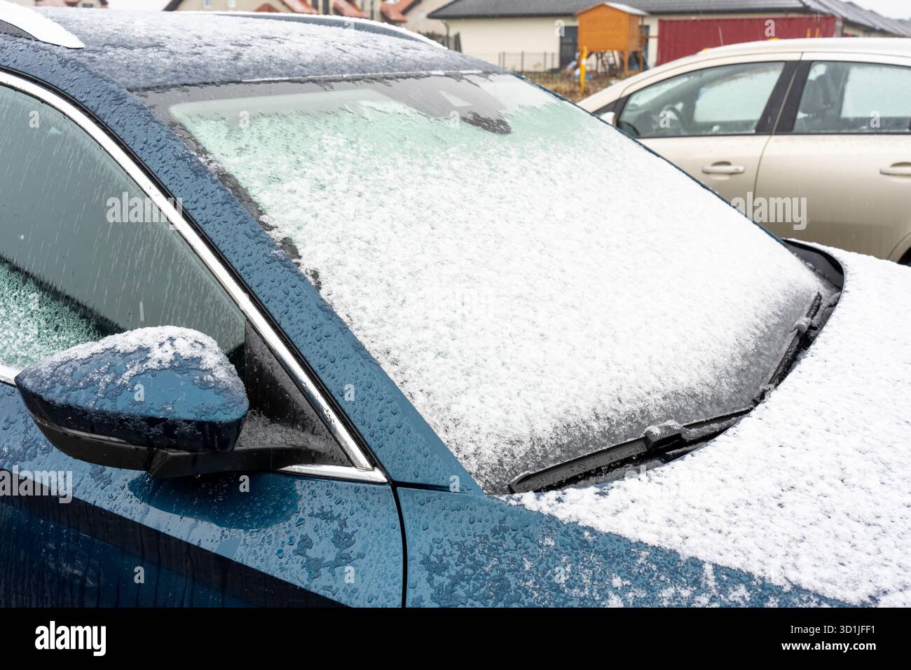 Pare-brise de voiture gelé couvert de glace épaisse et de neige dans le stationnement d'hiver avec d'autres véhicules dans le quartier résidentiel. Concept de défi par temps froid Banque D'Images