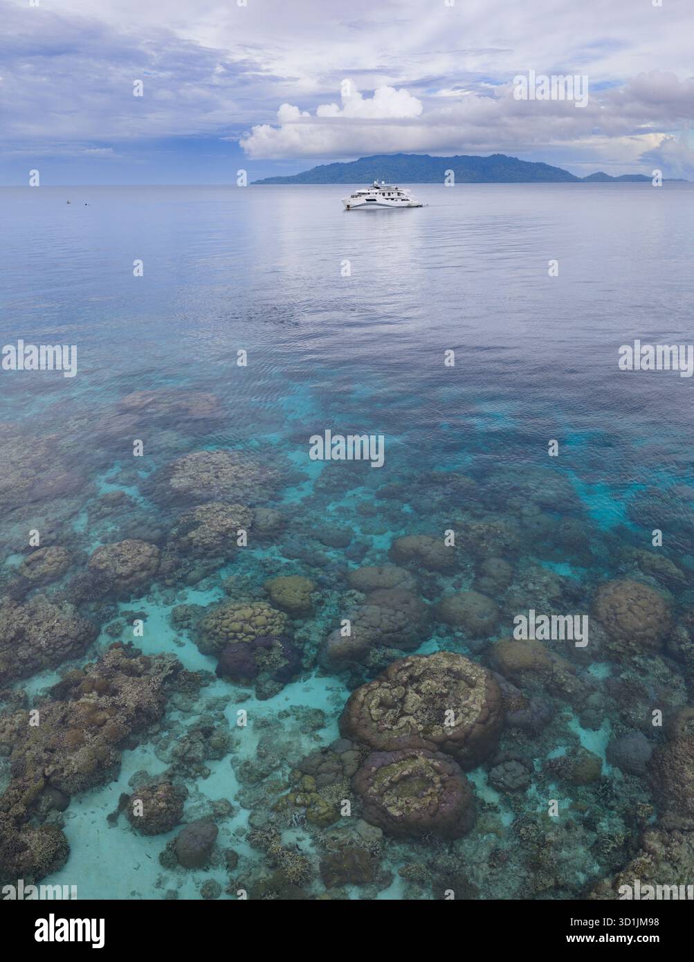 Un bateau de plongée dérive en eau libre, non loin du bord d'un magnifique récif corallien bordant Pulau Hatta dans les pittoresques îles Banda en Indonésie. Banque D'Images