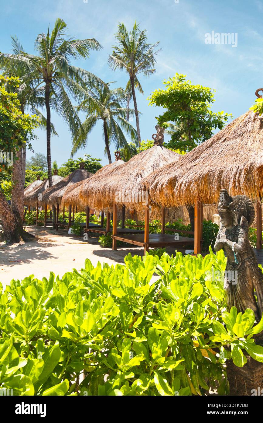 Une belle station balnéaire sur l'île tropicale de Bali en Indonésie. L'ombre du soleil est fournie par les cabanes de plage sous les palmiers Banque D'Images