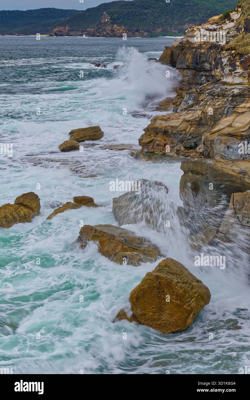 Les vagues sauvages de l'océan s'écrasent le long des falaises et de la côte rocheuse par jour couvert au parc national de Bouddi, Nouvelle-Galles du Sud, Australie Banque D'Images