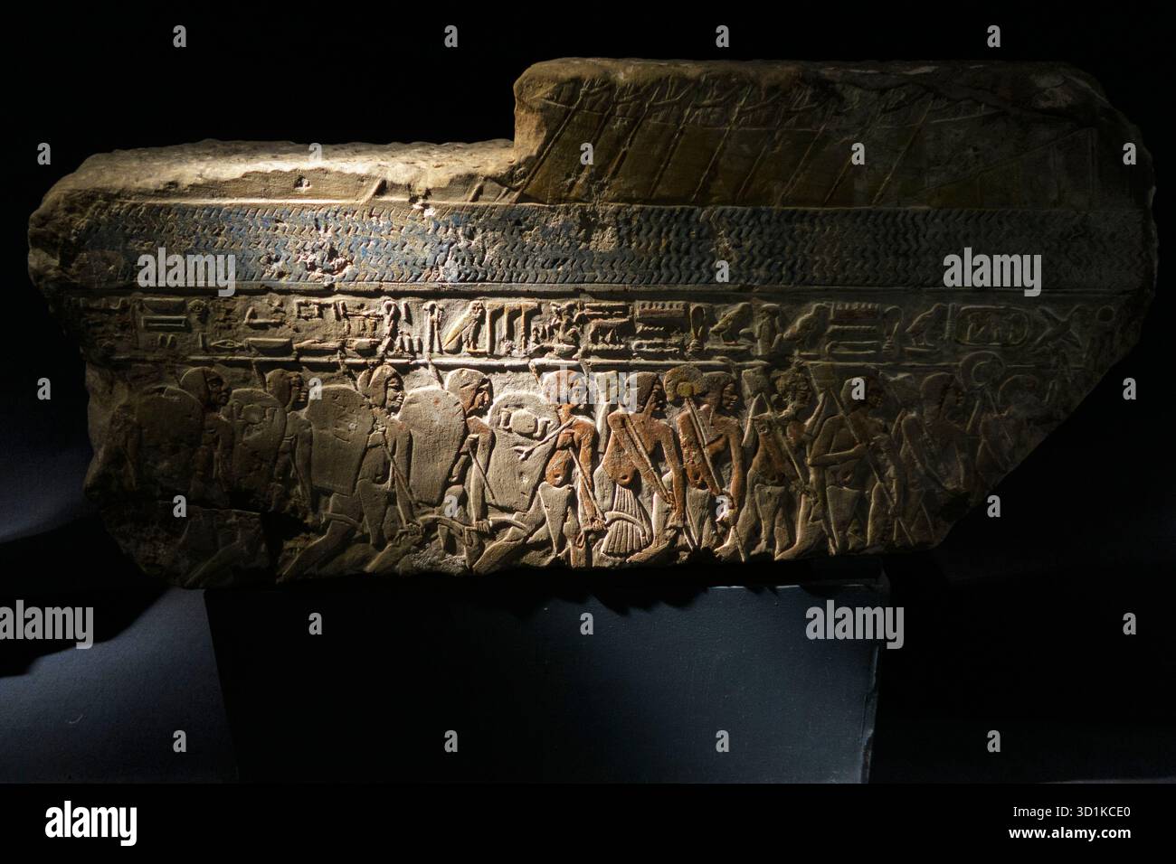 Fragment en relief de pierre égyptien antique avec des sculptures détaillées de figures humaines et de hiéroglyphes exposés dans un cadre de musée Banque D'Images