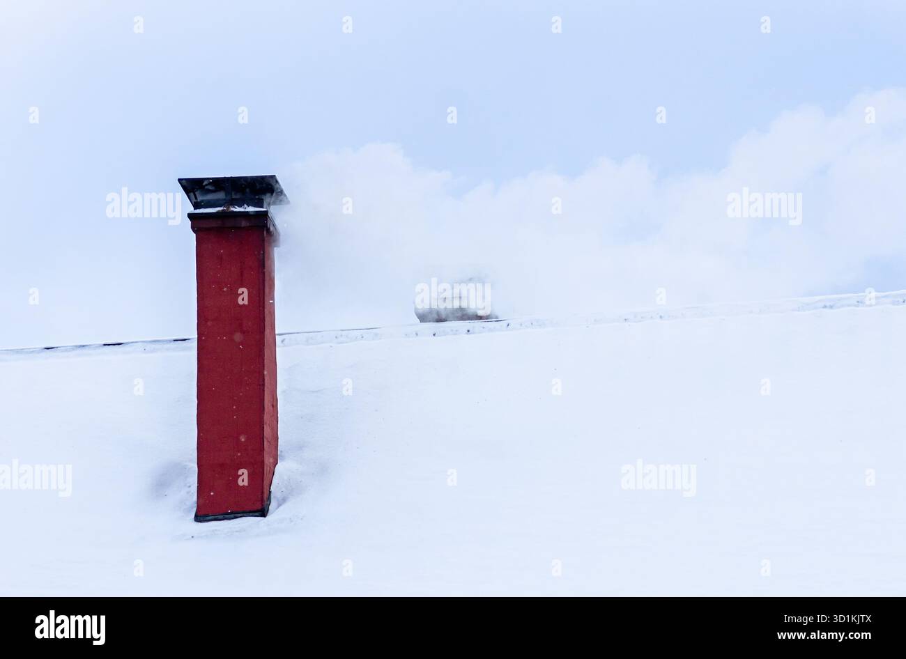 La fumée monte de la cheminée en brique sur le toit blanc enneigé en hiver. Chauffage domestique chaud, temps froid, scène de campagne paisible, concept d'énergie et de confort. Banque D'Images