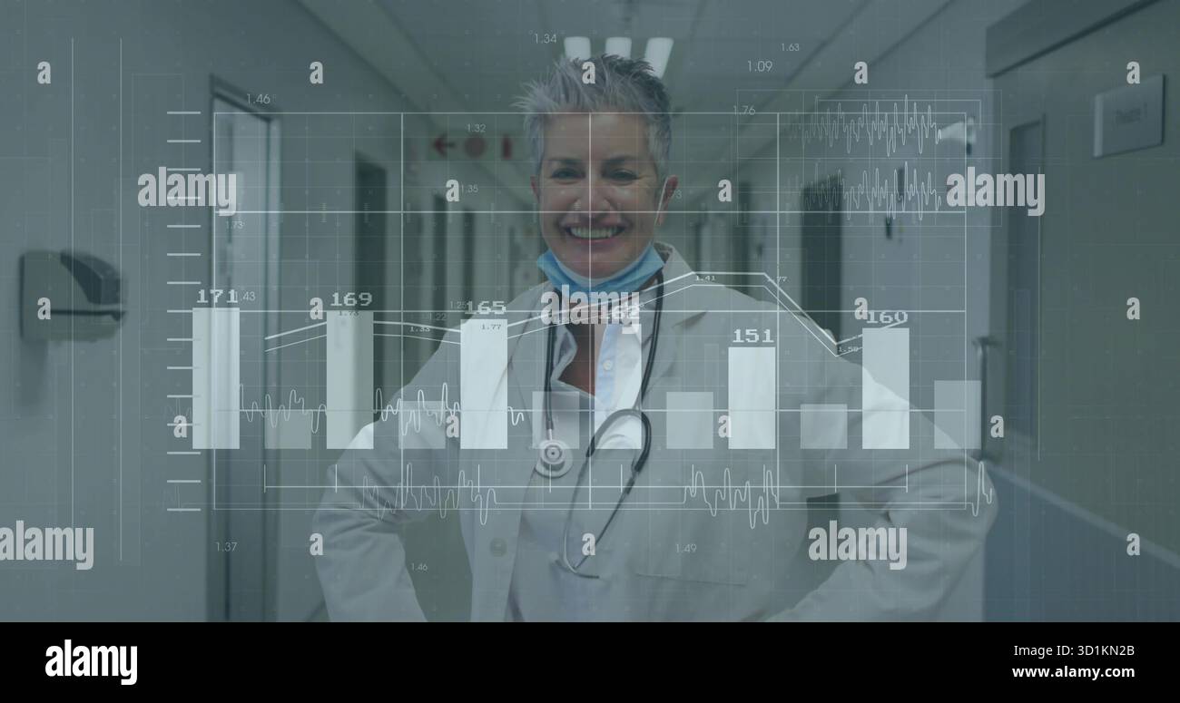 Médecin senior debout portant un manteau, stéthoscope dans le couloir de l'hôpital, avec masque, distributeur, graphiques Banque D'Images