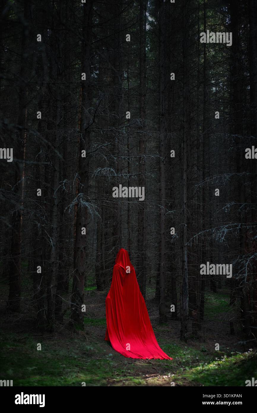 figurine vêtue d'un manteau rouge coulant se promène dans une forêt dense. Les grands arbres créent une atmosphère sombre tandis que la lumière s'estompe avec l'approche crépusculaire Banque D'Images