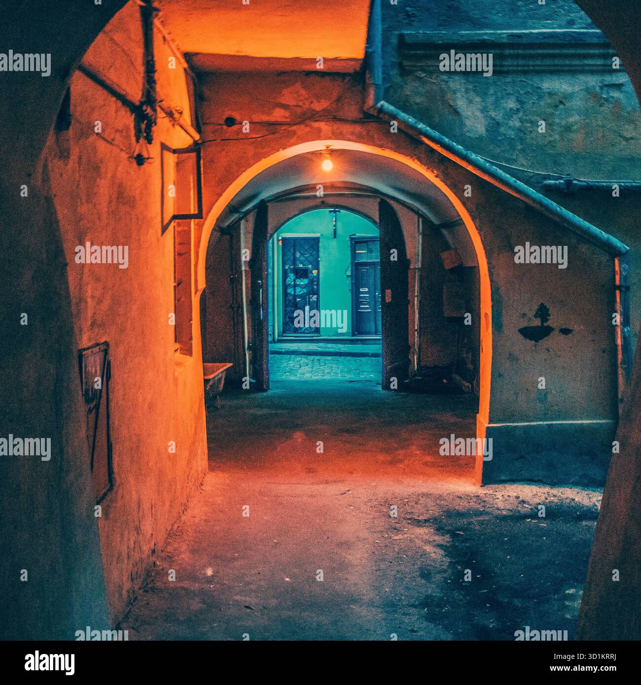 L'image représente un passage en forme de tunnel à l'intérieur d'une structure de bâtiment, caractérisé par des ouvertures arquées. L'éclairage projette une lueur orange chaude Banque D'Images