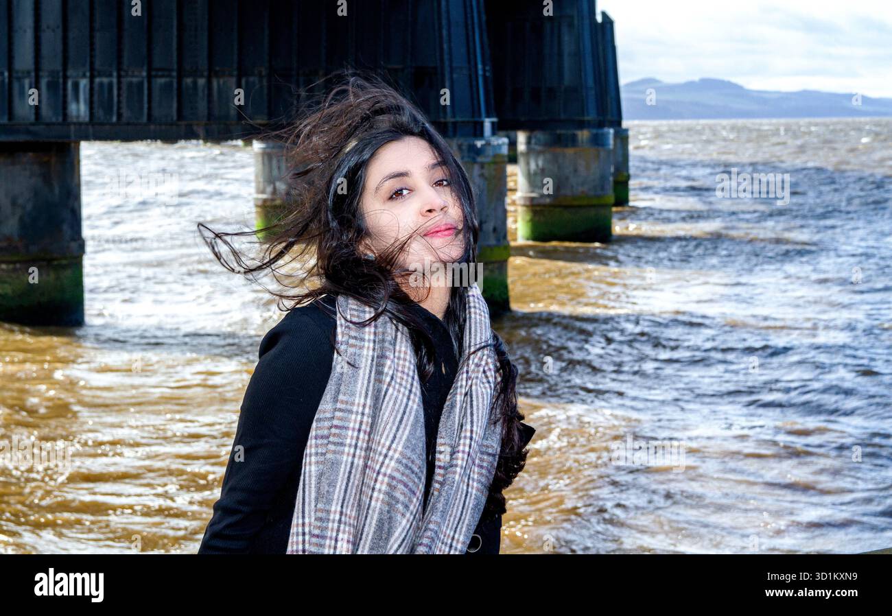 Le long de la rivière Dundee dans le soleil d'hiver une belle femme avec de longs cheveux bruns soufflant dans des rafales de vent, en Écosse Banque D'Images
