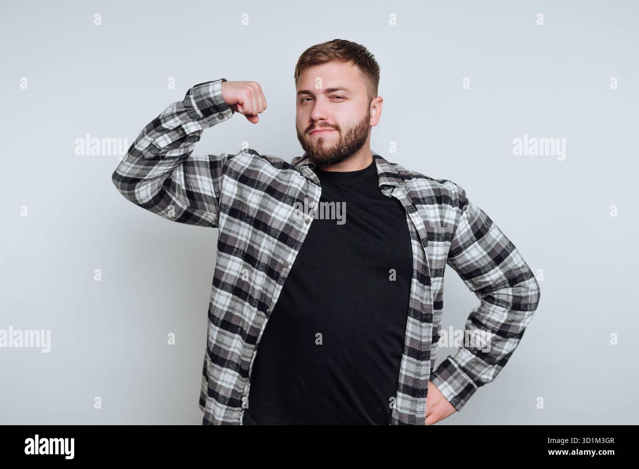 Un homme confiant dans une chemise à carreaux fléchissant son biceps. Banque D'Images