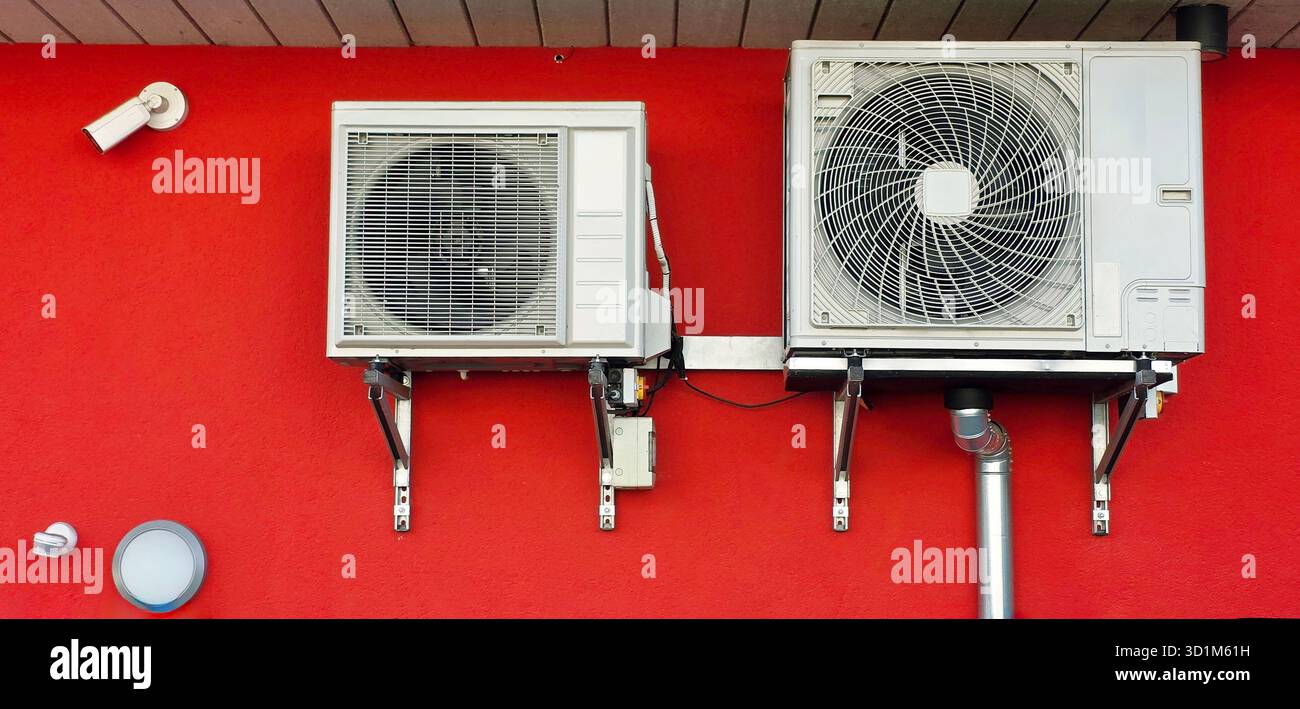 Les unités de climatisation sont montées sur un mur, présentant un fond rouge vif, mettant en valeur la technologie de refroidissement moderne et les éléments de conception. - Image de stock capturée avec un smartphone