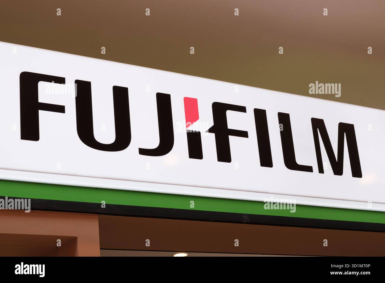 Le logo Fujifilm apparaît bien en évidence sur une enseigne de magasin, avec des couleurs noire et rouge sur fond blanc. Un éclairage lumineux améliore la visibilité Banque D'Images