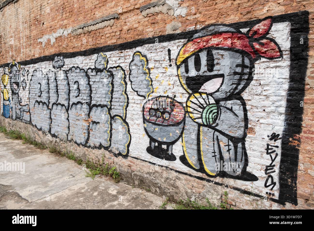 Le Street art vibrant sur un mur de briques représente un personnage humoristique savourant un repas, apportant de la couleur et de la vivacité au paysage urbain. Banque D'Images