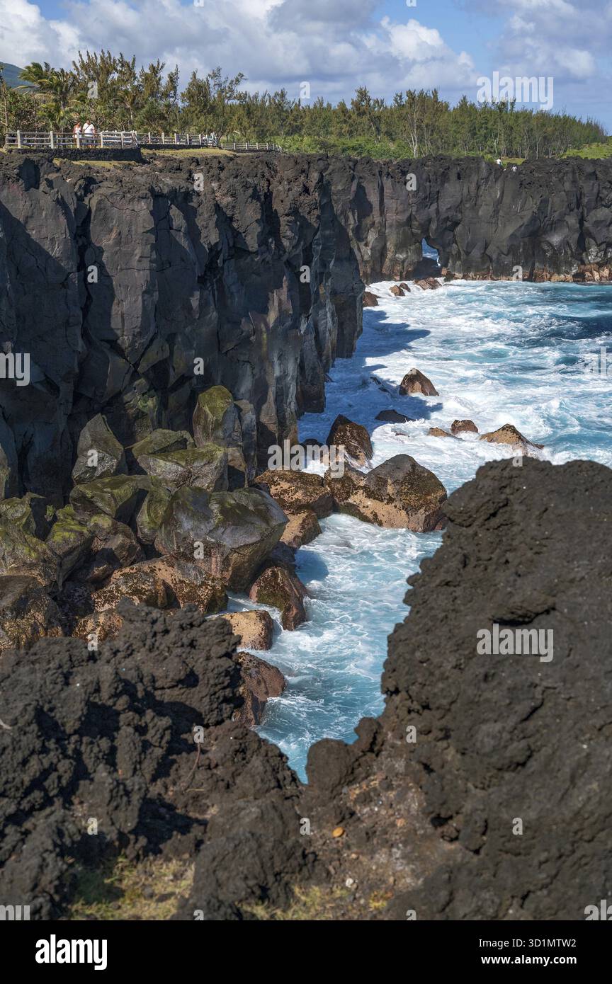 Des falaises de lave noires massives s'élèvent abruptement hors de l'océan Indien à Cap Mechant, où des vagues blanches baignent autour de la roche volcanique, tandis que dans l'arrière-pays Banque D'Images